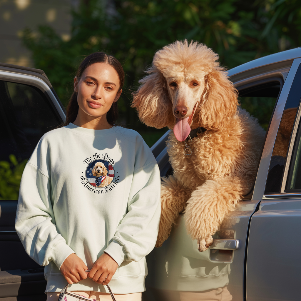 Wear-it-around Poodle collection image showing a young lady wearing a light colored sweatshirt featuring a poodle with an American flag background with the words "we the Dogs". Beside her is a large standard poodle leaning out of the window of a car.
